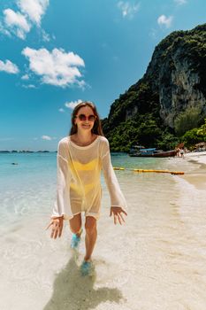 Woman enjoying a sunny day at the beach on Ko Panyi, Phang Nga, Thailand, with clear blue skies.