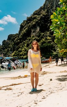 A woman in a yellow swimsuit enjoys a sunny day at Ko Panyi beach, Phang Nga, Thailand.