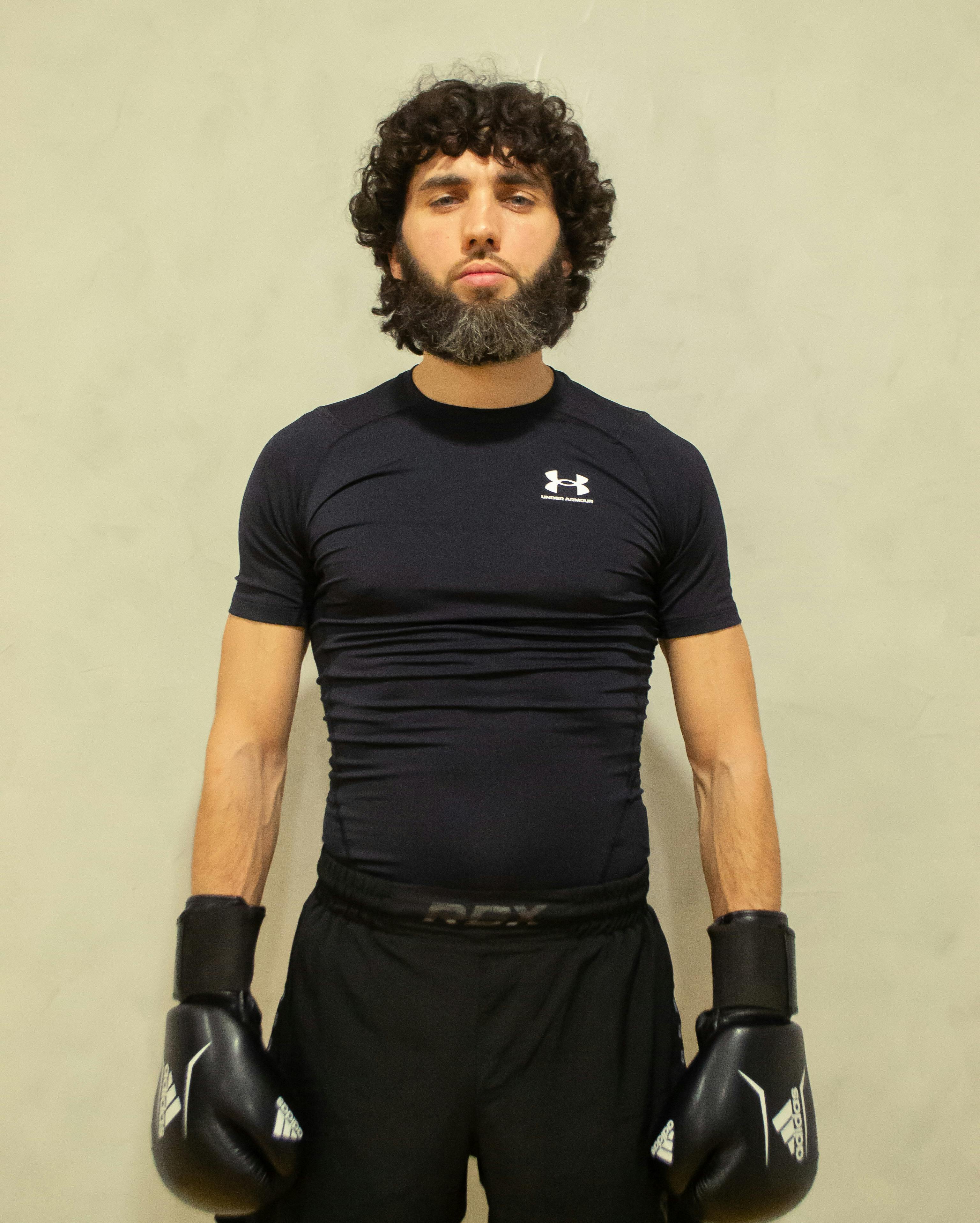 A male boxer with gloves poses confidently indoors, showing focus and determination.