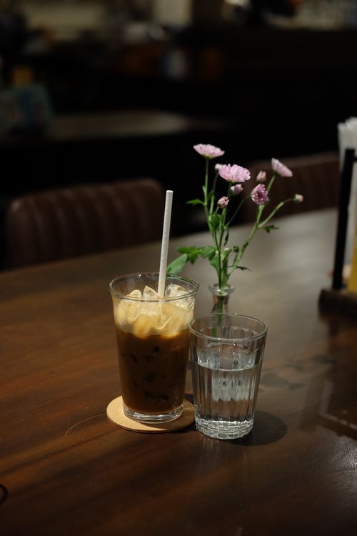 Free A cozy setting with iced coffee, water, and fresh flowers on a table. Stock Photo