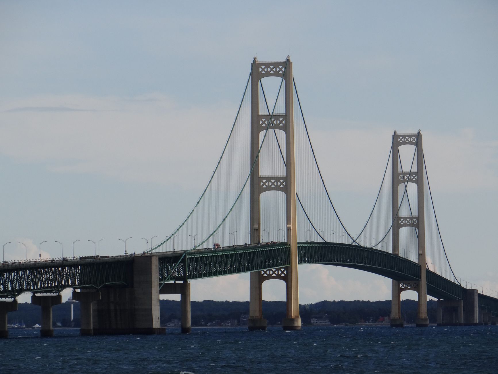 Impressive view of the Mackinac Bridge stretching across Lake Michigan under a clear blue sky, taken in St. Ignace, MI.
