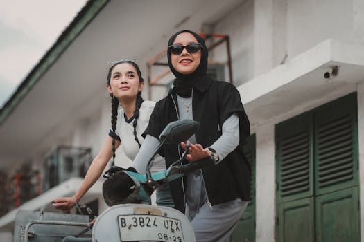 Two stylish young women on a vintage scooter enjoying a sunny day outdoors.