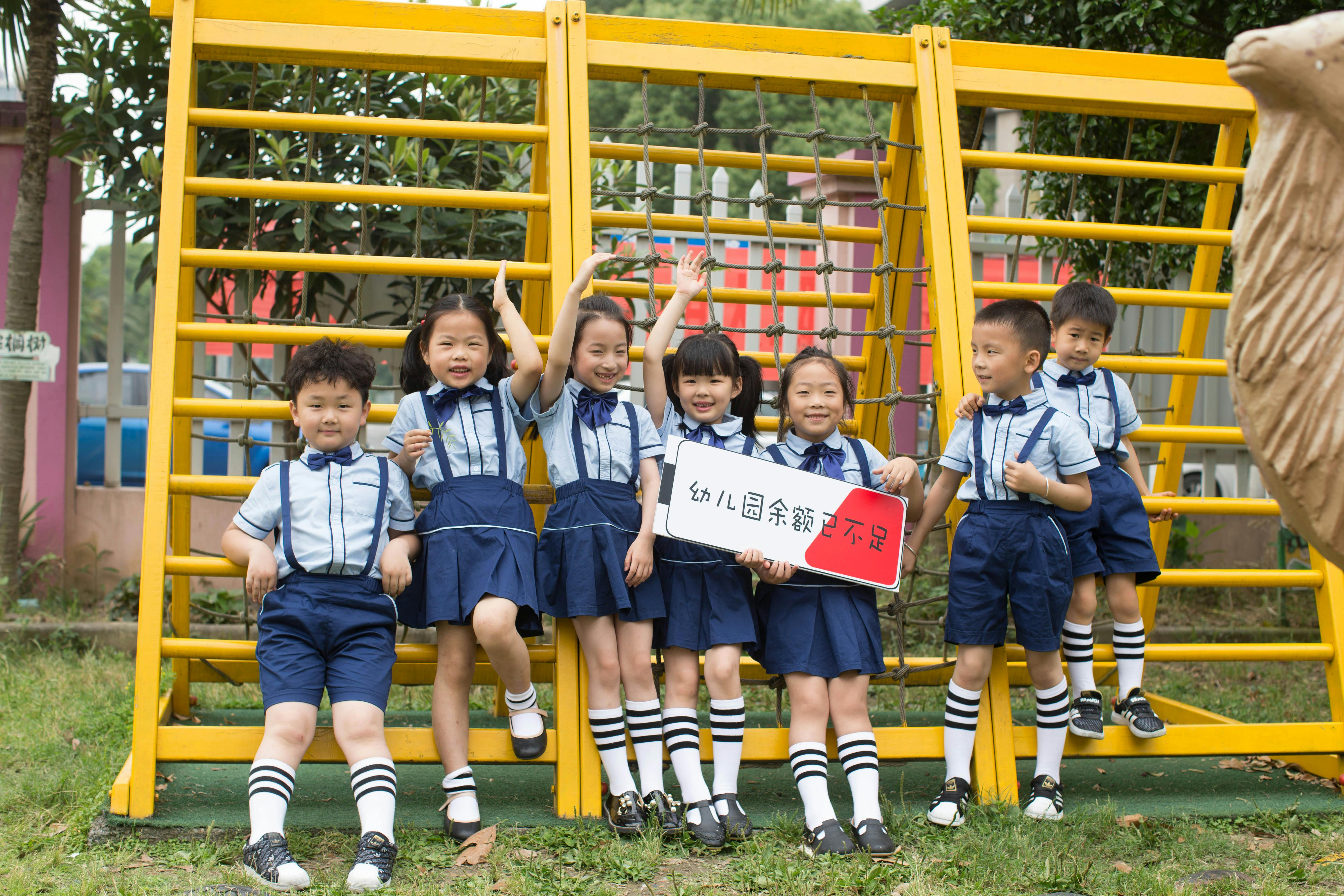 Cheerful children in school uniforms playing outside by a climbing frame, enjoying a sunny day.