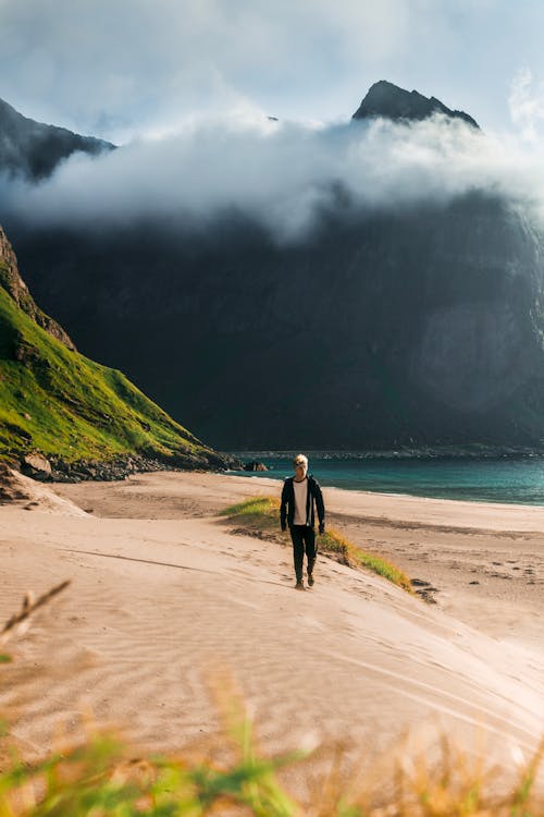 Man Walking On Sand Beside Seashore