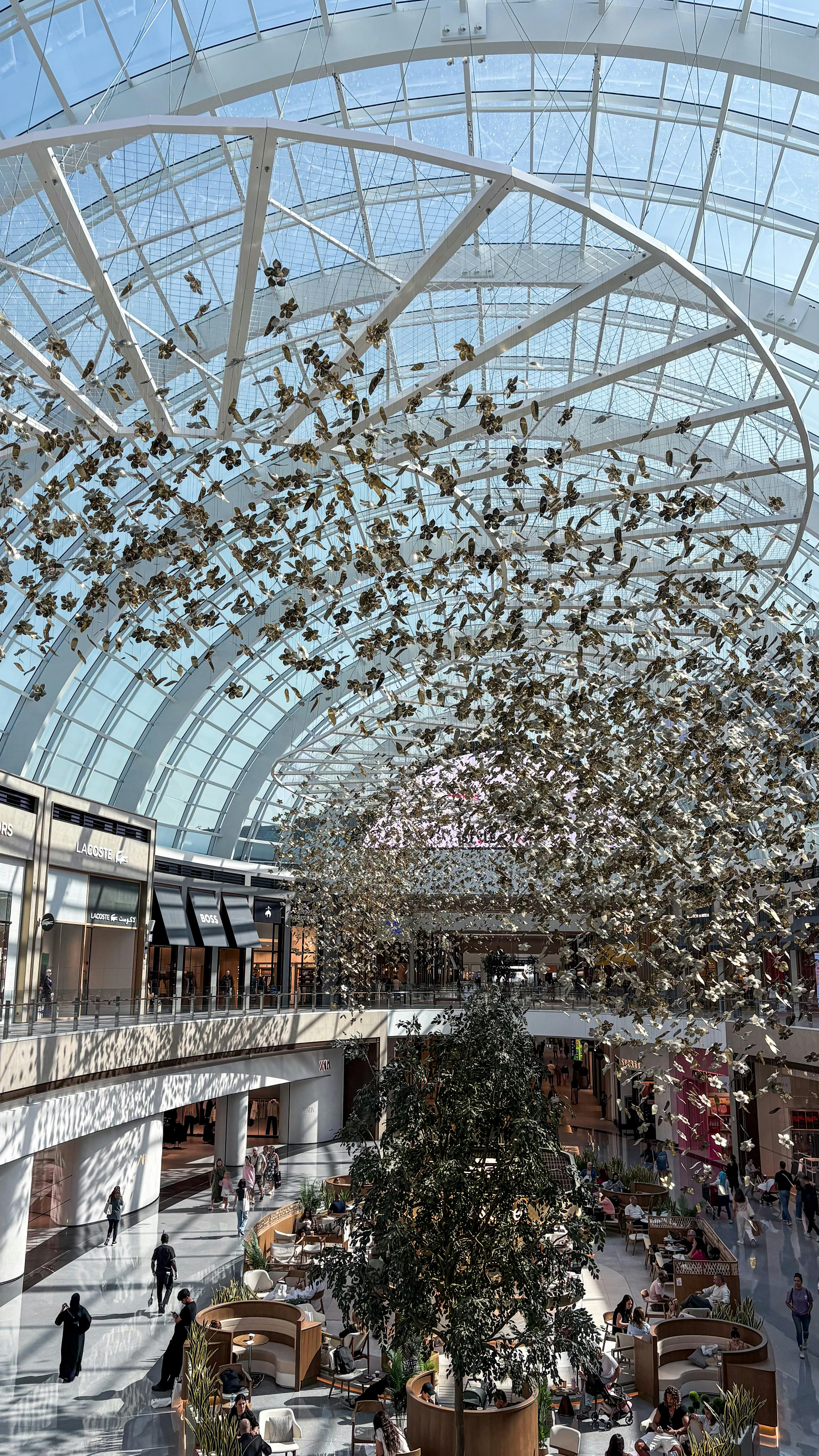 Stunning interior view of a modern mall with a glass ceiling and intricate hanging art.