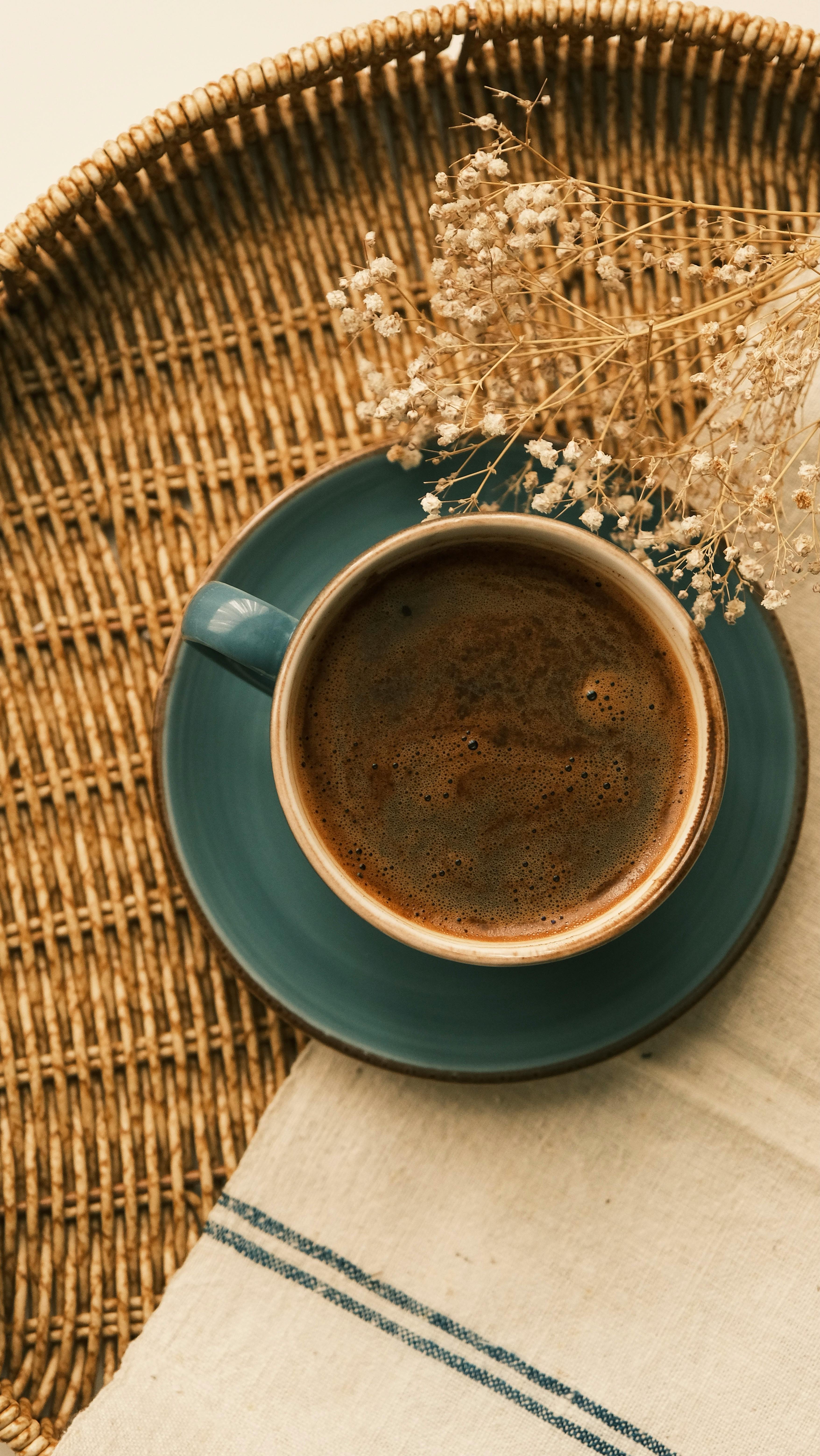A cozy scene with a cup of coffee on a woven tray, accented by dried flowers.