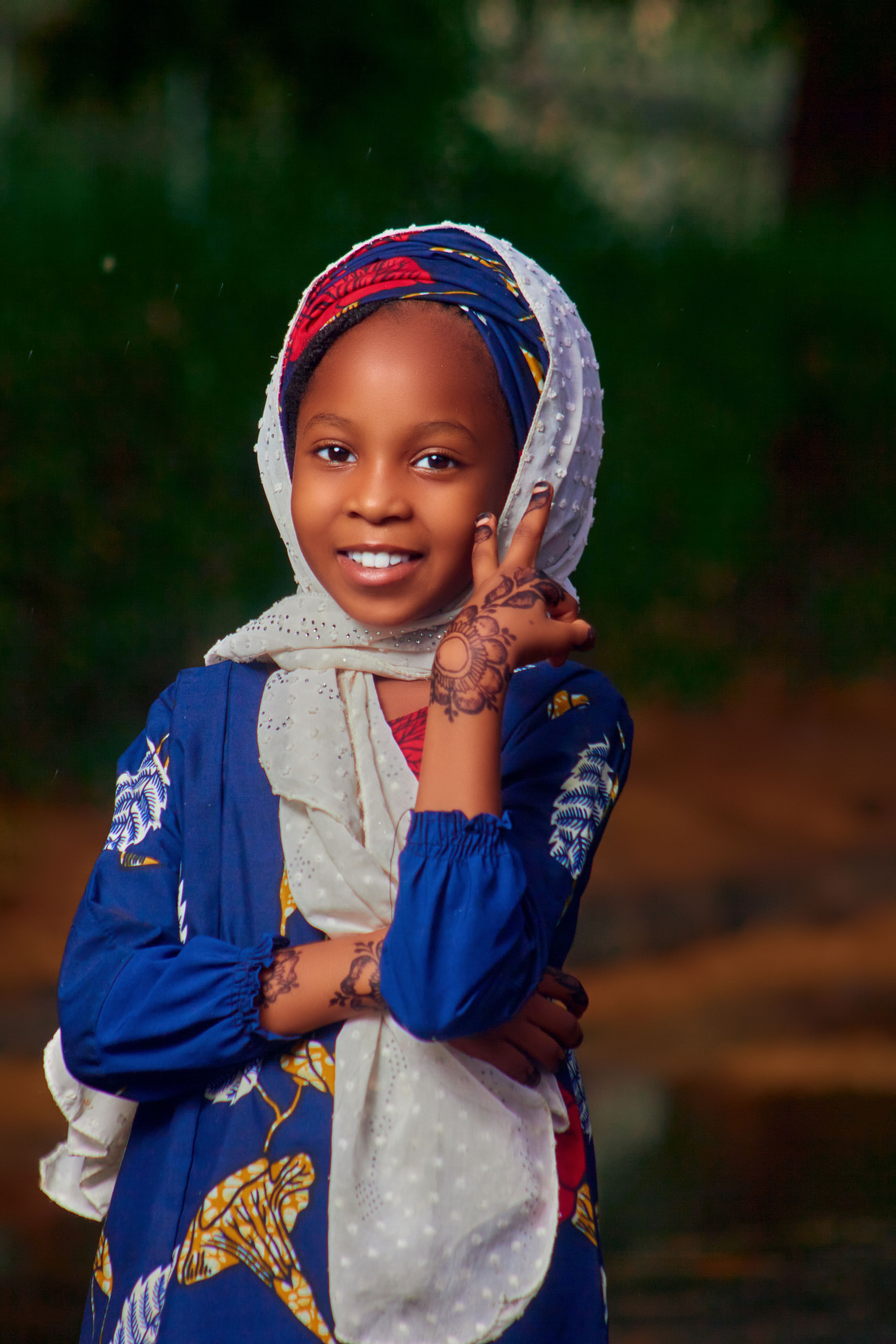 Young girl smiling brightly, wearing traditional attire with henna designs.