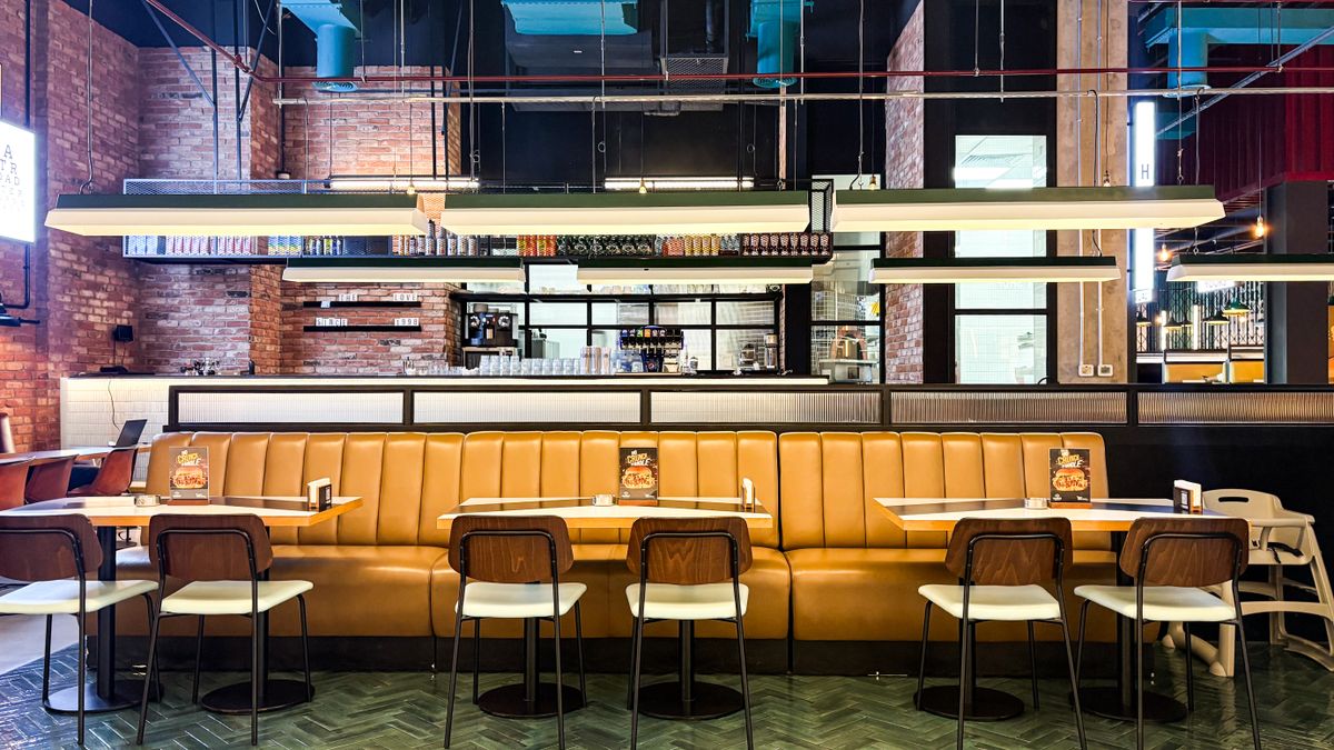 Restaurant interior with brown leather seating and an open kitchen.