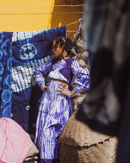 Free Woman in vibrant clothing poses confidently against a background of colorful fabrics. Stock Photo