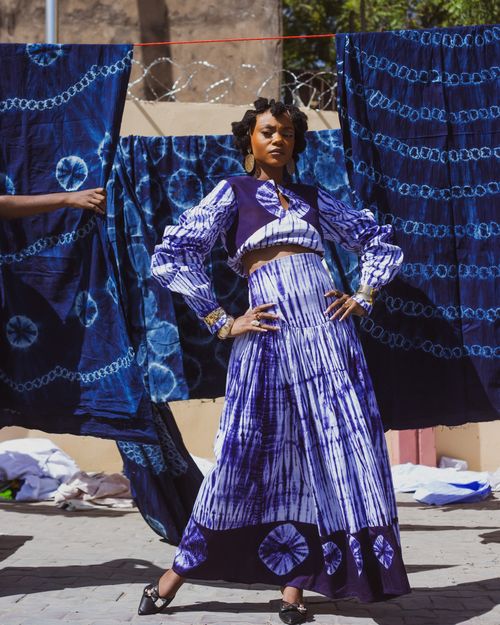 Free Elegant portrait of an African woman in traditional indigo attire outdoors with vibrant blue tie-dye fabrics. Stock Photo