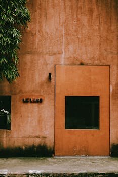 A minimalist exterior view of the Le Labo shop in Bangkok, Thailand, featuring a rustic design with green foliage.
