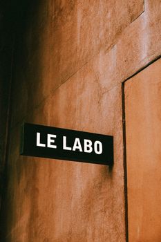Minimalist Le Labo sign on a textured wall, exuding urban rustic charm.
