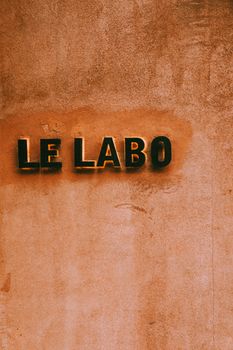 A minimalist image showcasing the Le Labo sign on a textured wall with warm tones.