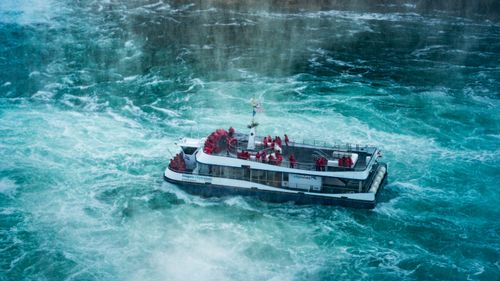 Free Tourists in red ponchos enjoy a boat tour at Niagara Falls in misty conditions. Stock Photo
