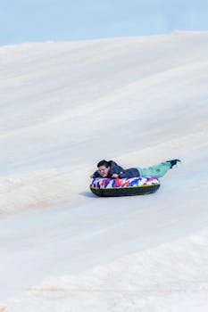 A person is snow tubing down a slope, showcasing winter fun in a snowy landscape.