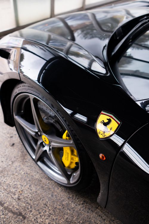 Free Detailed view of a sleek black sports car with a focus on its wheel and iconic logo. Stock Photo