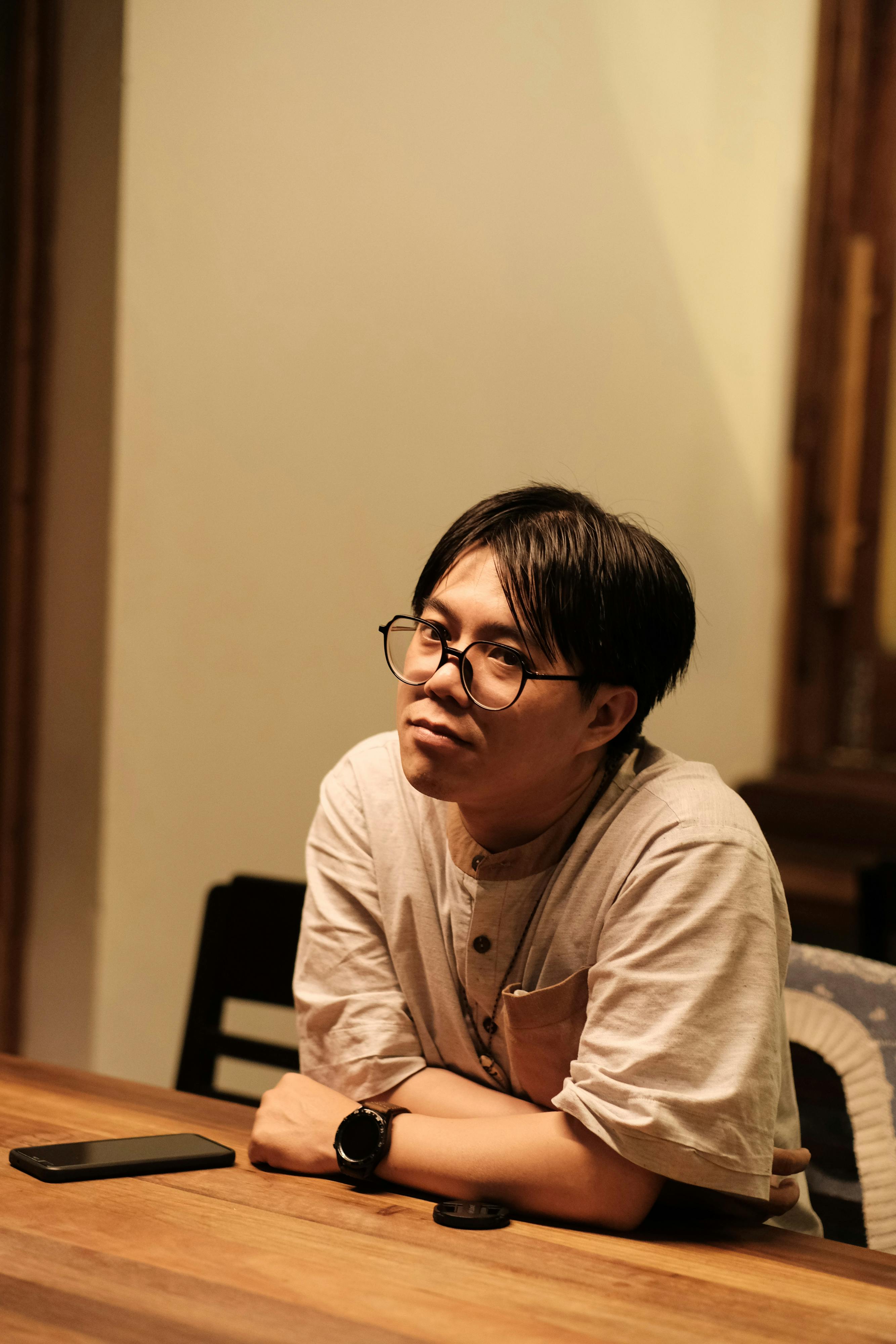 免費 一位沉思的男子坐在室內，將傳統風格與現代美學融合在一起。 圖庫相片