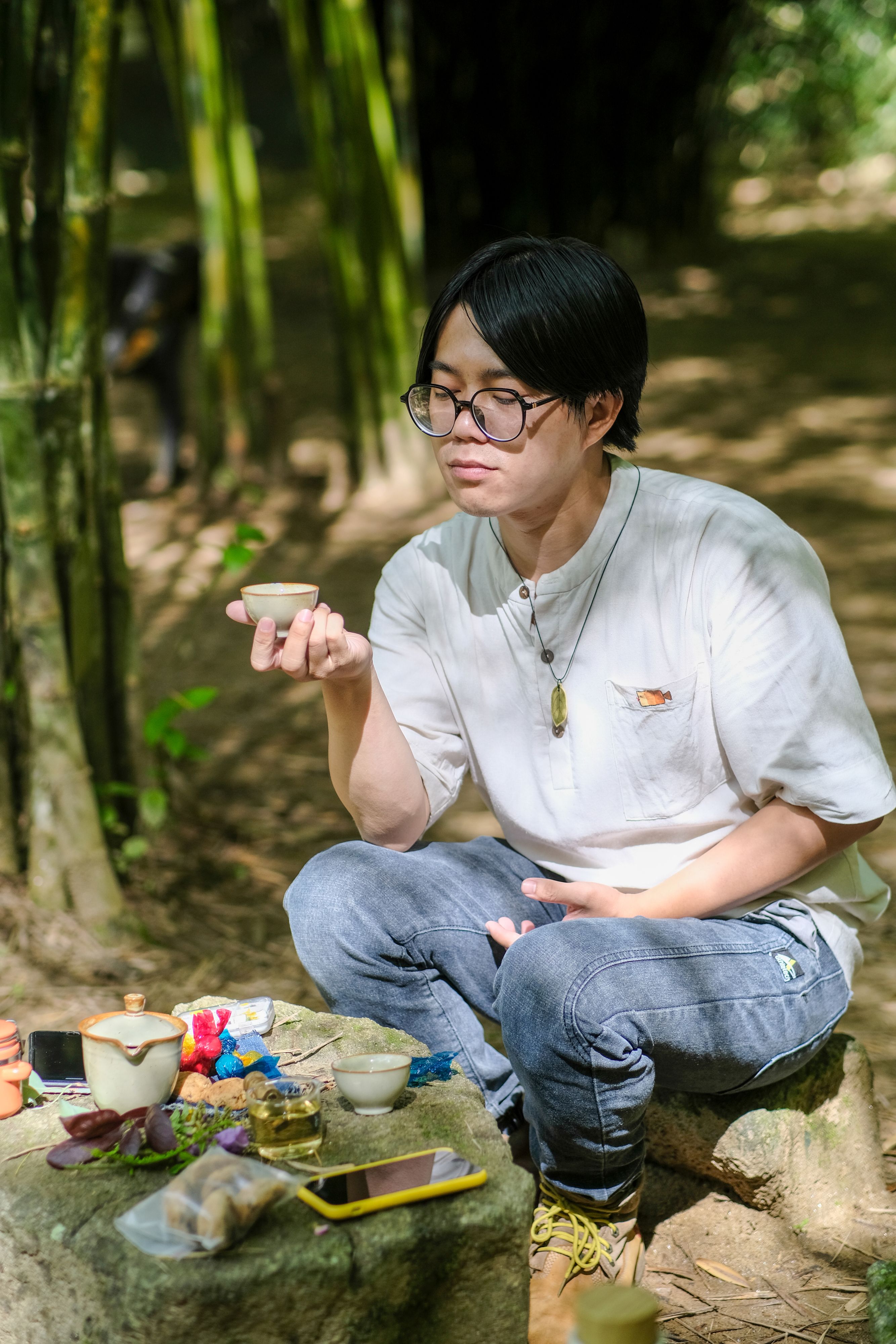 A man enjoys a peaceful tea ceremony in a lush bamboo forest in Hue, Vietnam.
