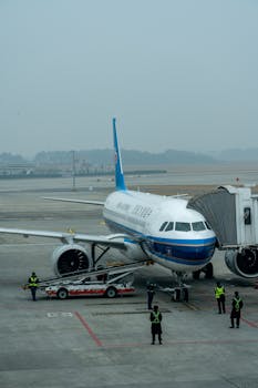 Airplane boarding at airport gate with crew members prepared for departure.