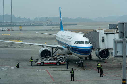 Passenger airplane docked at airport terminal with crew members working around it.