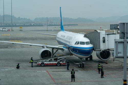 Free Passenger airplane docked at airport terminal with crew members working around it. Stock Photo