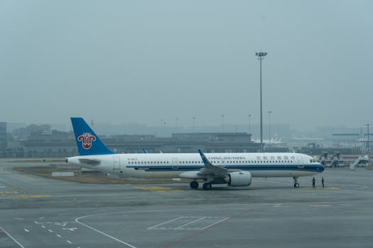 China Southern Airlines Airbus A321 parked at the airport on a foggy day.