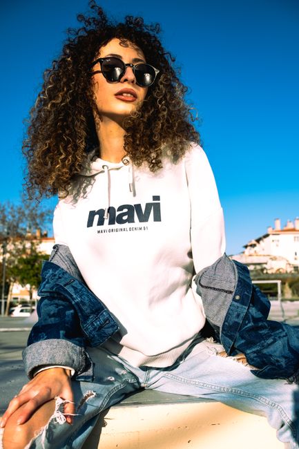 Stylish woman in sunglasses posing outdoors in casual wear on a sunny day.