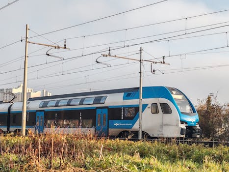 A modern passenger train passing through Ljubljana, Slovenia, on a sunny day.