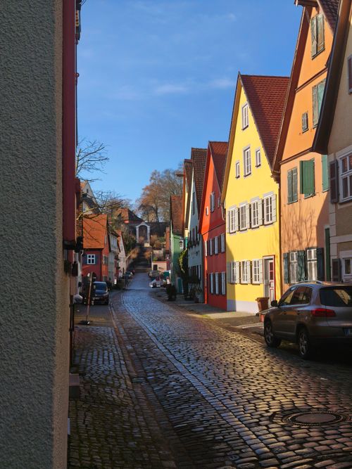 Free Colorful houses line a cobblestone street in a quaint European village under a clear blue sky. Stock Photo