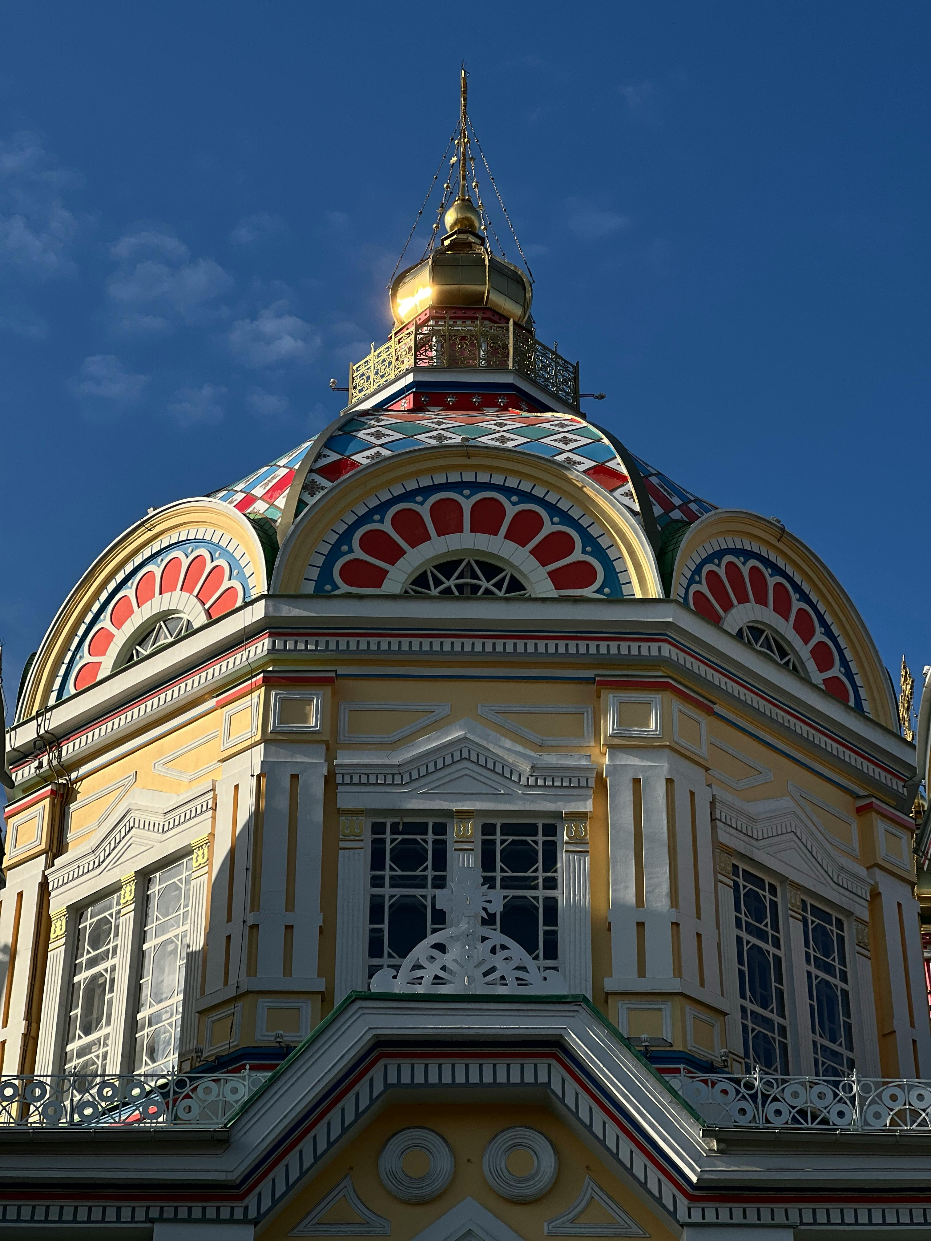 Ücretsiz Karmaşık bir şekilde dekore edilmiş bir binanın tepesindeki canlı altın kubbe, berrak mavi gökyüzü fonunda. Stok Fotoğraflar