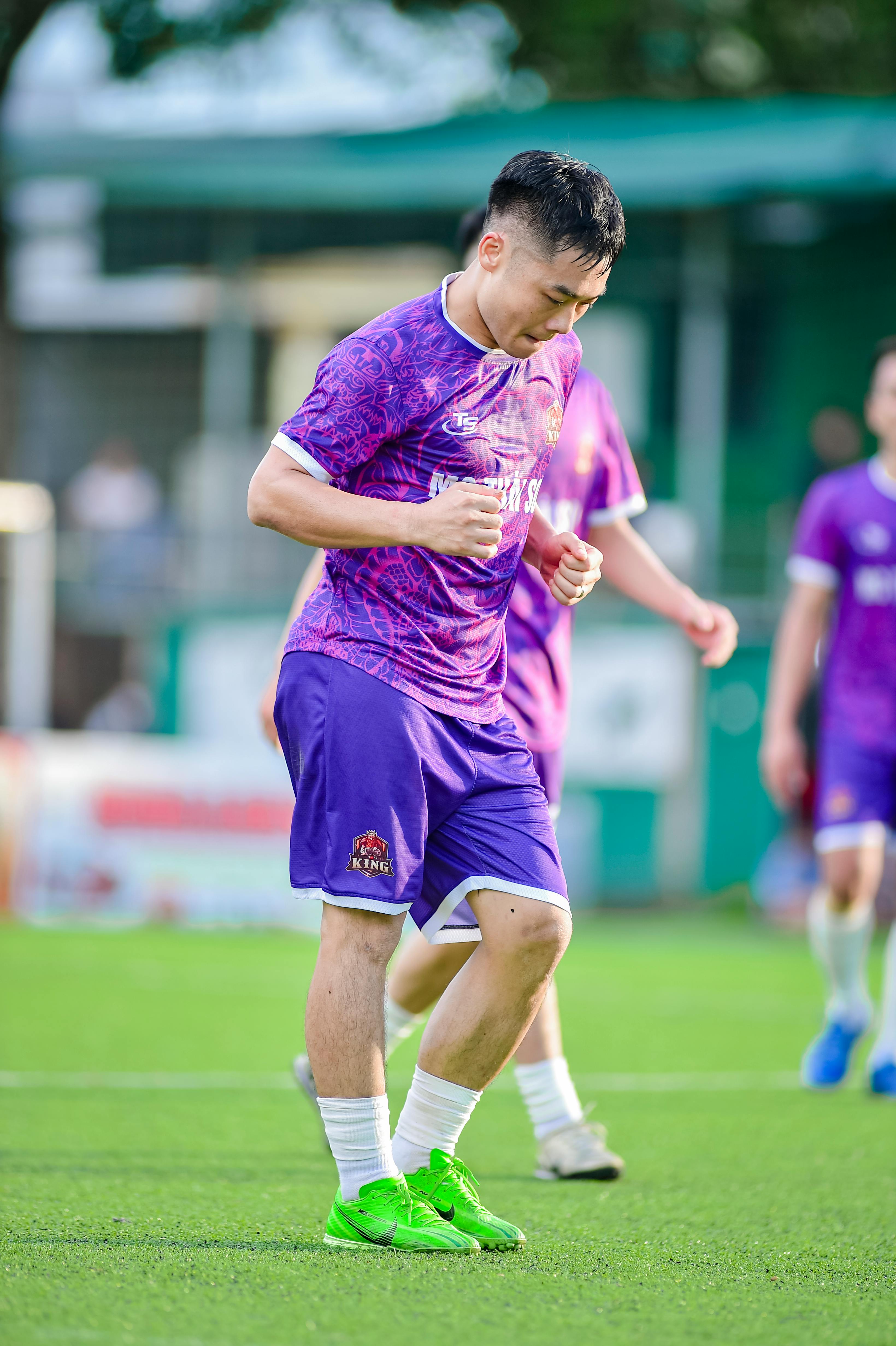 Young athletes in purple uniforms playing soccer outdoors in Hanoi, Vietnam.