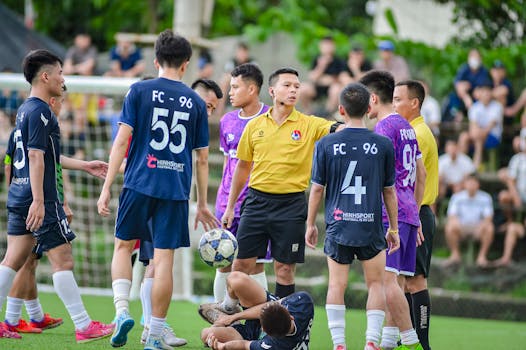 Dynamic scene of a youth football match with referee in Hà Nội.