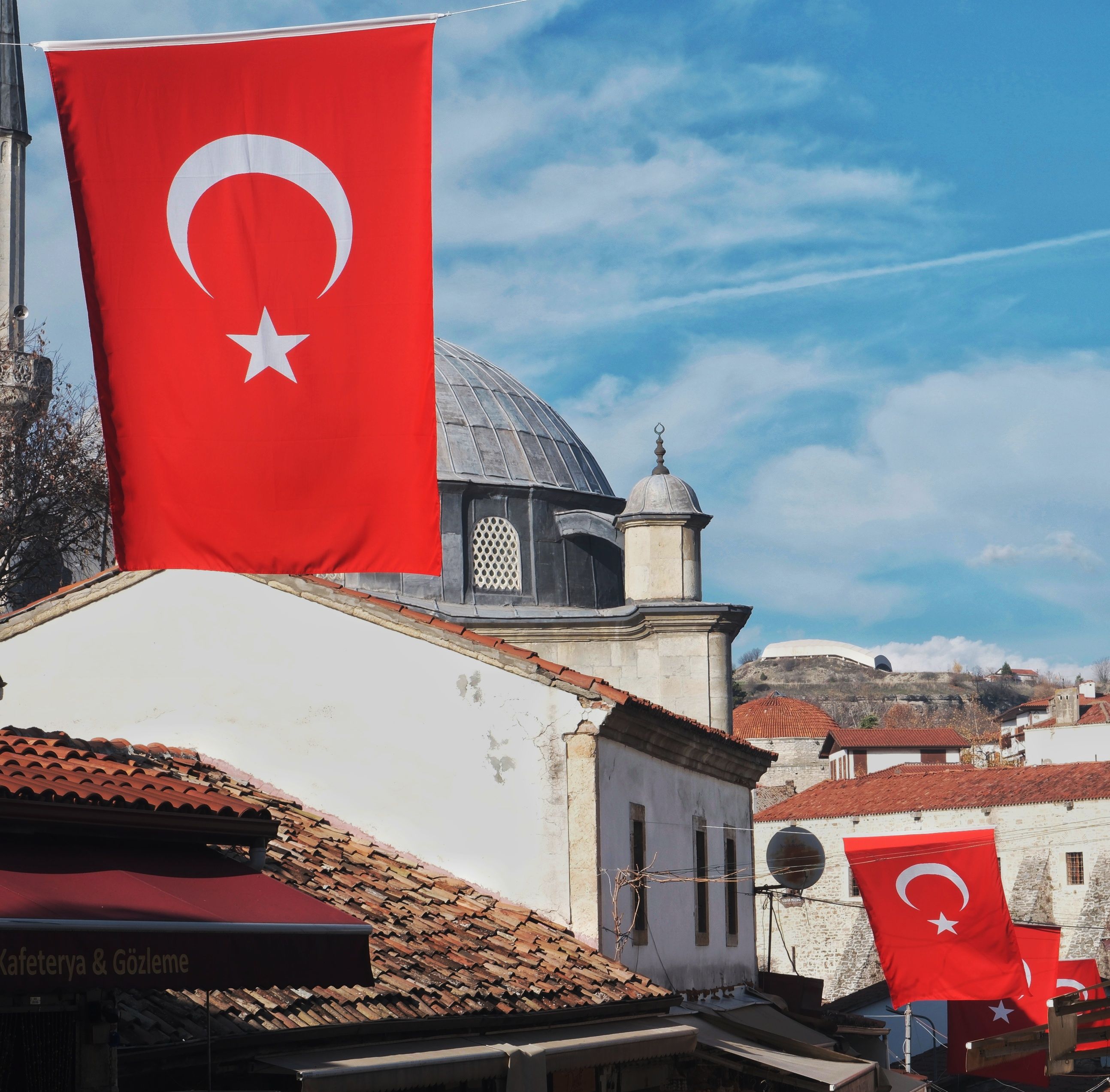 Black Flag Resynced Rekor Kırdı: 2 Milyon Oyuncu Sınırını Aştı! - Red Turkish flags flutter next to traditional architecture under a blue sky in Turkey.