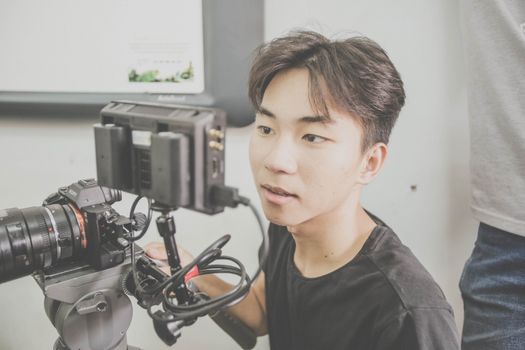 Portrait of a young adult using professional camera equipment in an indoor setting.