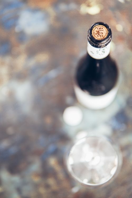 Free Elegant top view of a wine bottle with cork and blurred glass, showcasing luxury and refinement. Stock Photo