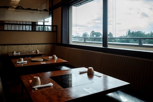 Cozy interior view of a traditional Japanese restaurant in Kyoto, featuring wooden tables and a scenic outdoor view.
