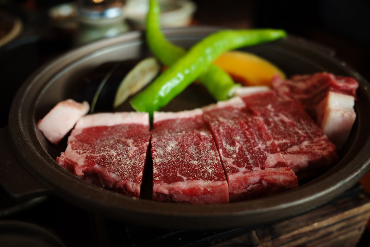 Finely marbled wagyu beef slices on a cast iron grill — Yonezawa beef, one of Japan's three great wagyu varieties