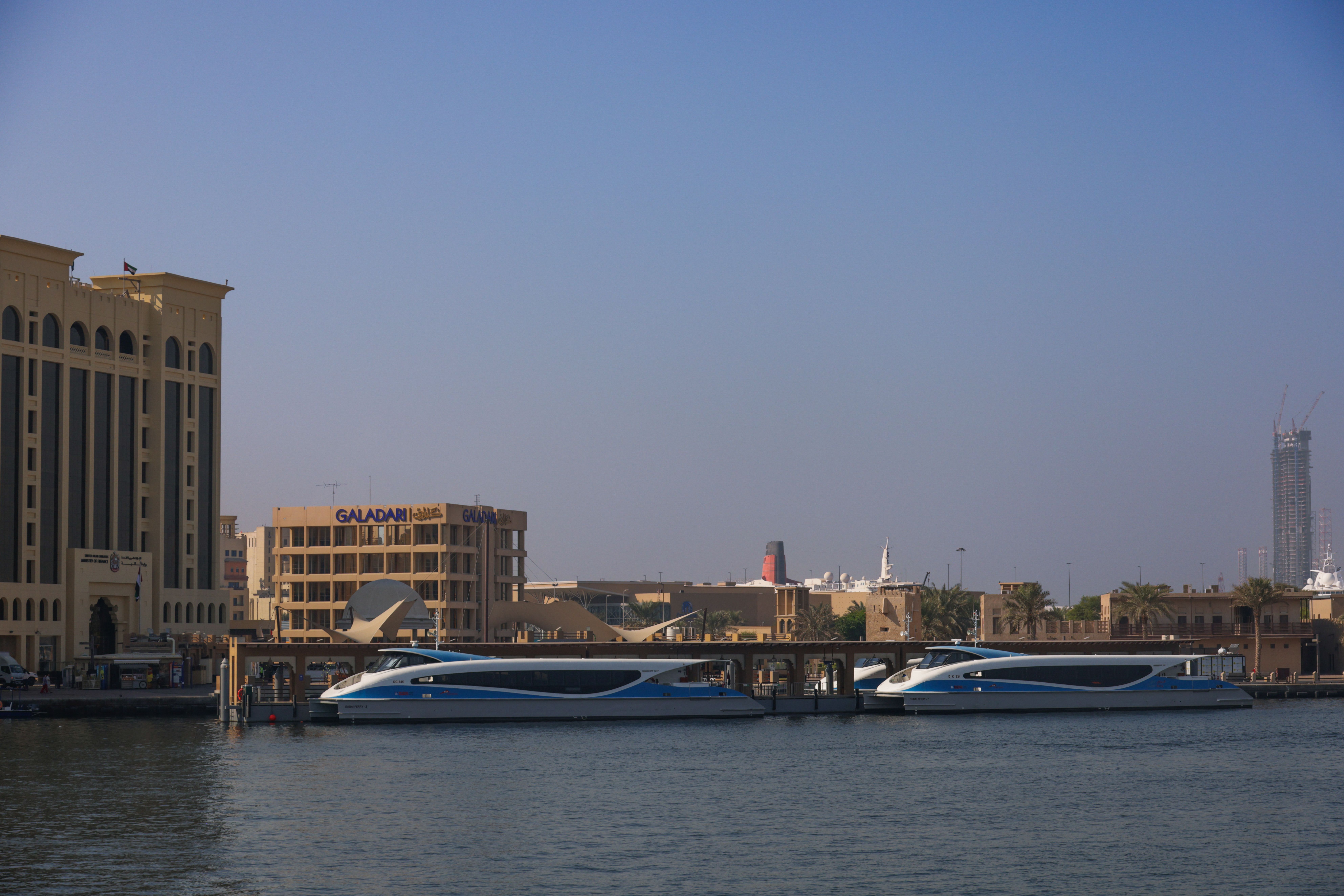 Sleek boats on the tranquil waters of Dubai Creek with iconic architecture in the background.
