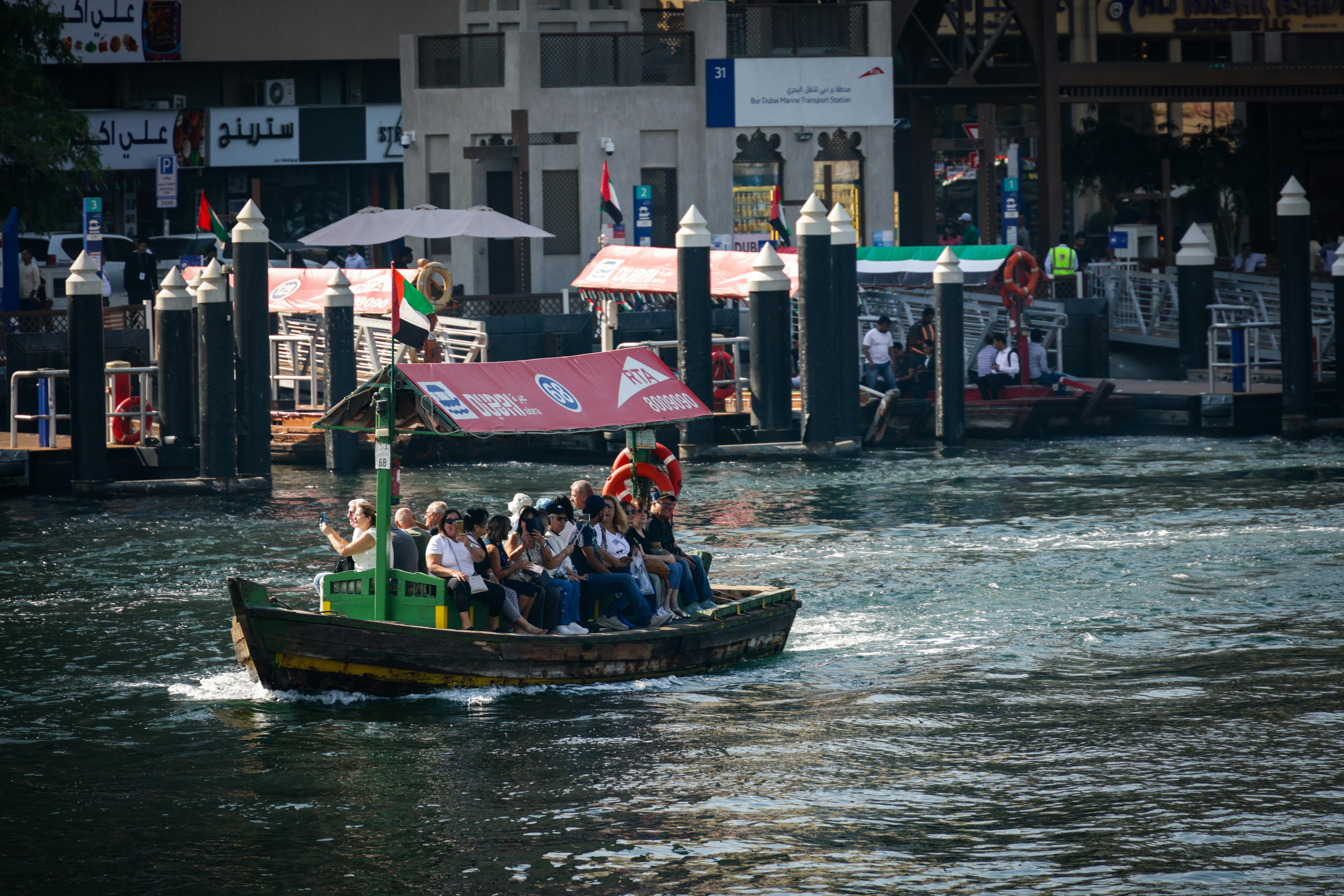 A scenic view of people enjoying a ride on a traditional abra boat along Dubai Creek.