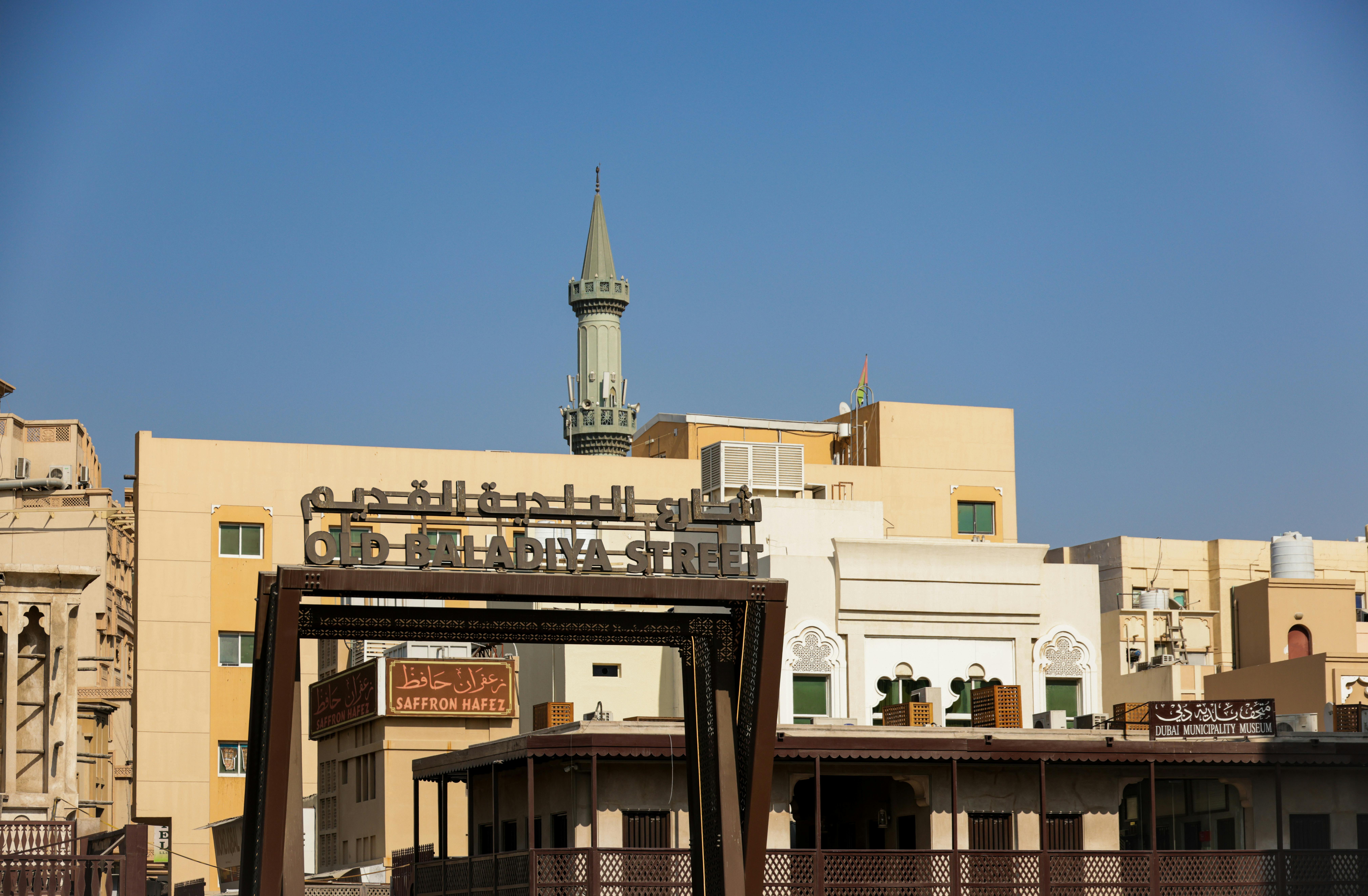 A scenic view of Old Baladiya Street featuring traditional architecture and a minaret in the backgro