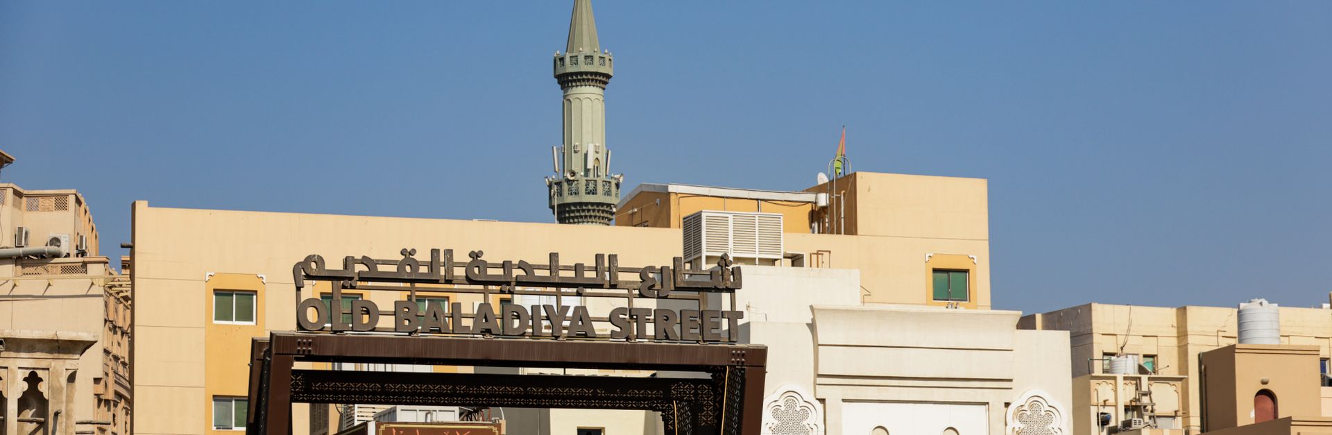 A scenic view of Old Baladiya Street featuring traditional architecture and a minaret in the backgro