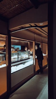 Warmly lit bakery with people choosing delicious pastries on display.