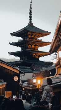 Captivating view of a traditional pagoda in Kyoto, Japan at twilight with people in kimonos walking nearby.