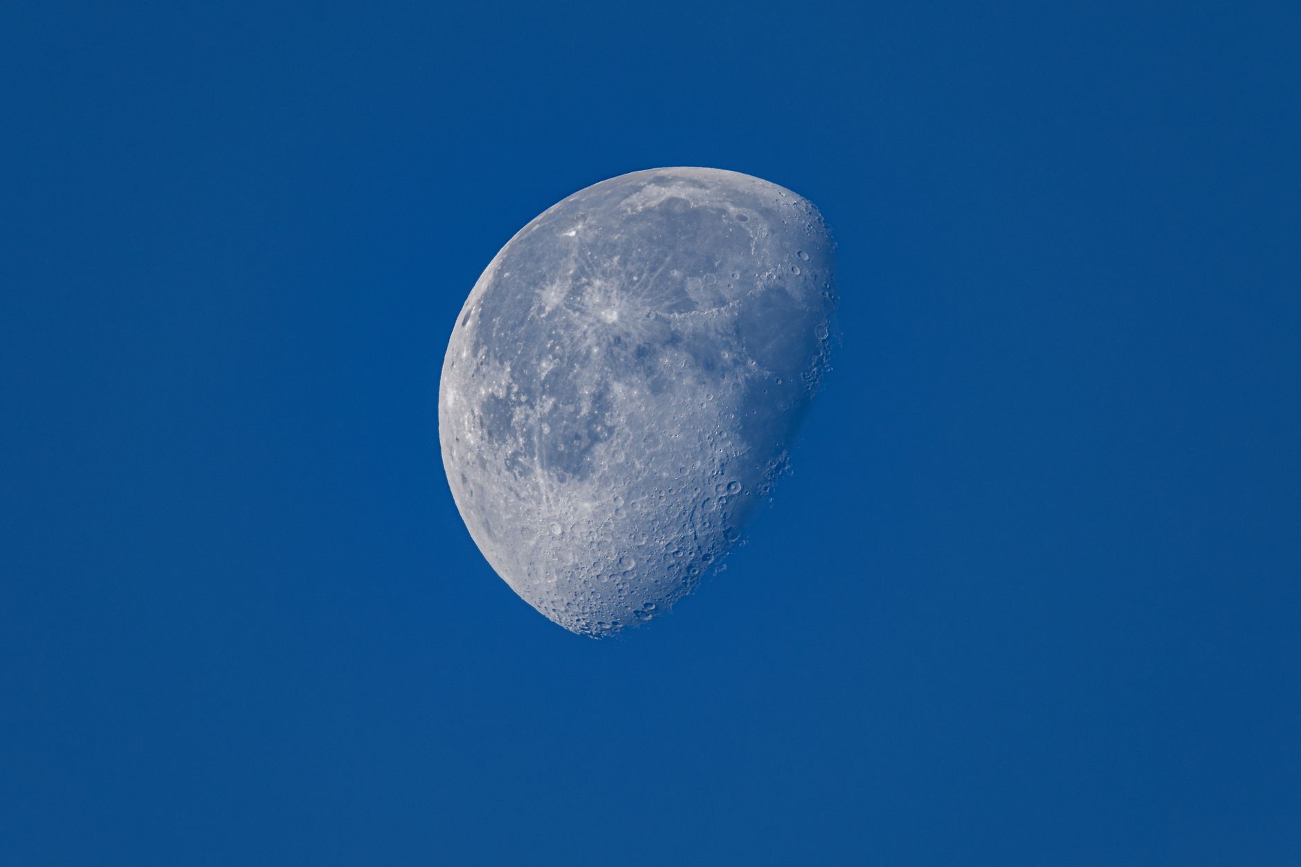 Detailed view of the moon in a clear blue sky with visible craters.