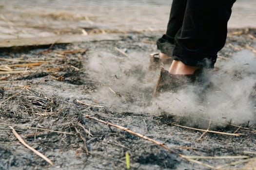 Piedi che camminano su un terreno cinereo mentre il fumo sale, a rappresentare l'esterno e il mistero.