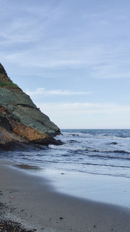 Free Breathtaking coastal view with rocky cliffs and gentle waves under a clear blue sky. Stock Photo