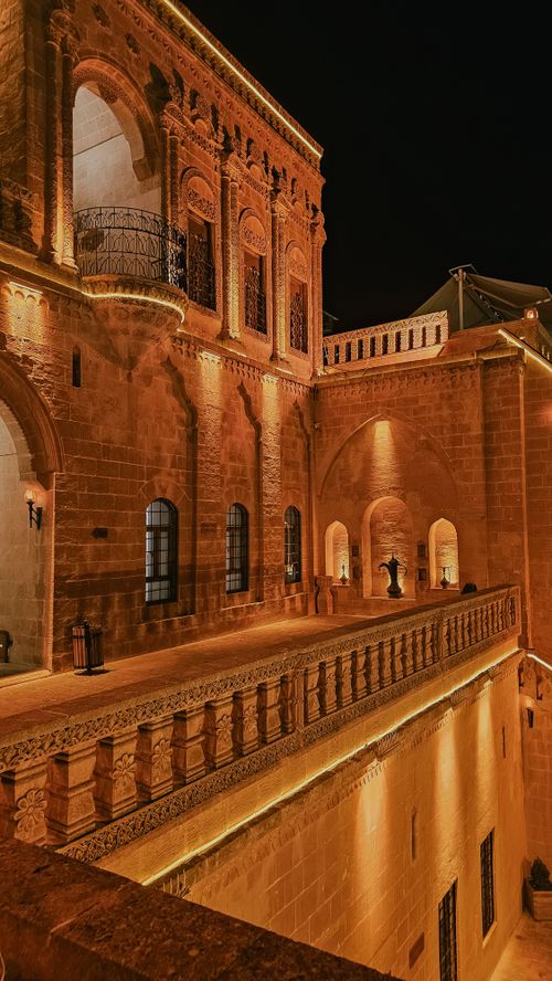 Free A stunning view of historic architecture illuminated with warm lights at night, showcasing intricate stonework and arches. Stock Photo