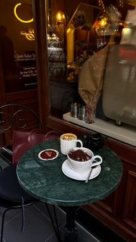 Warm and inviting cafe table with coffee and hot chocolate on a marble top table.