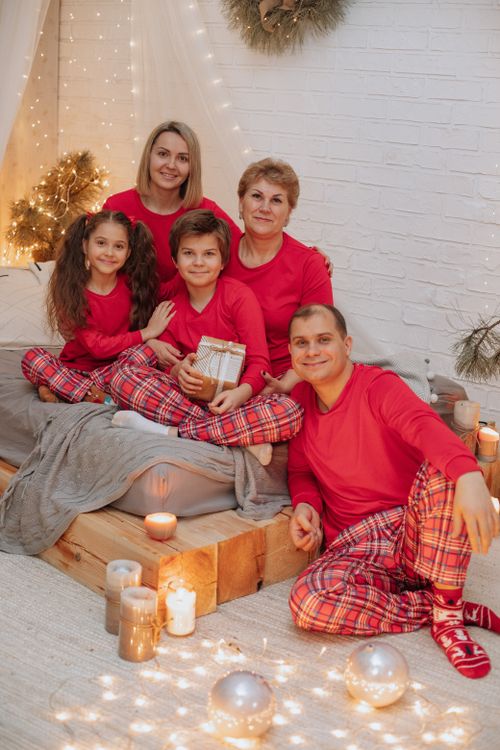 Free Family enjoys cozy Christmas ambiance with candles and matching pajamas indoors. Stock Photo