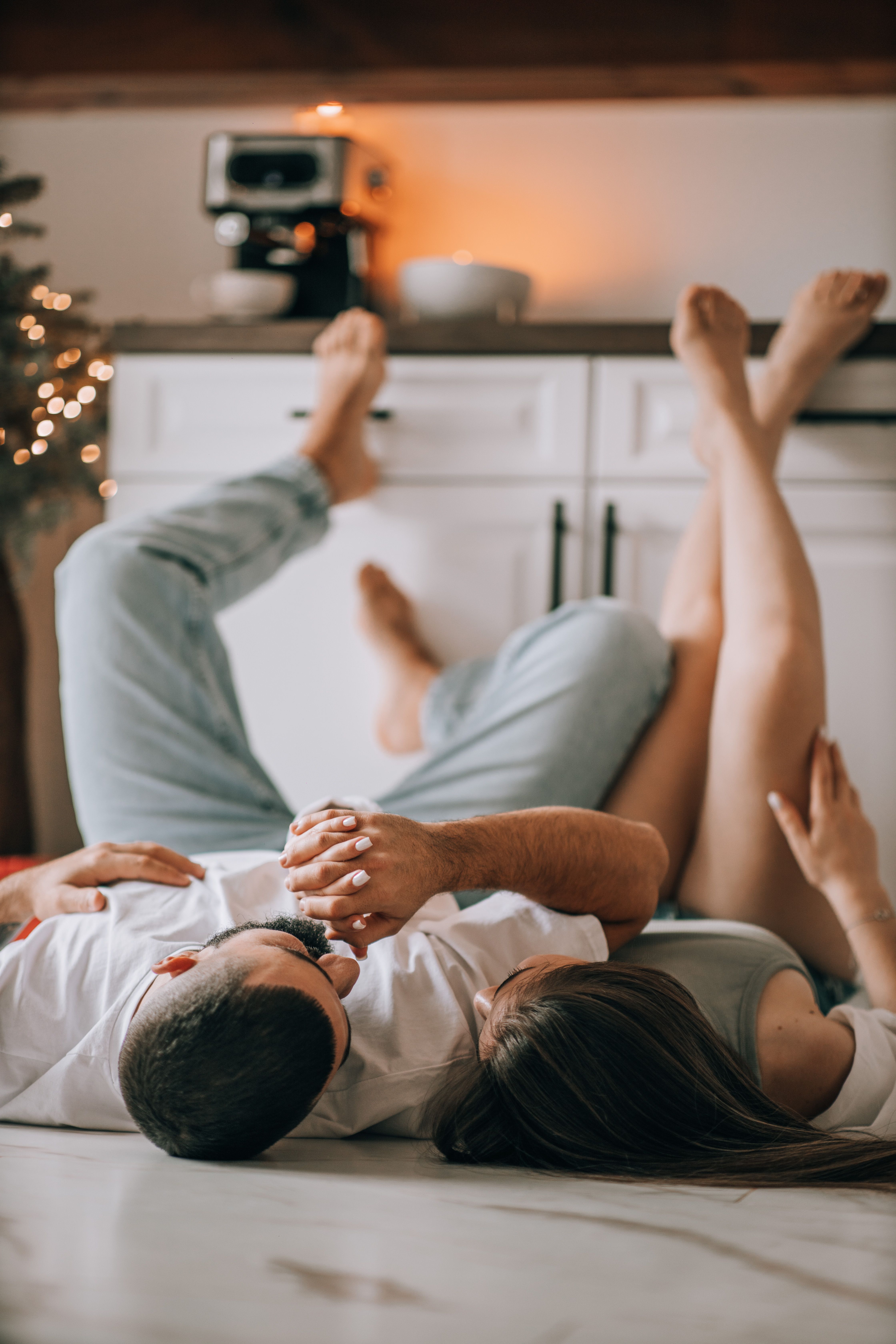 A couple enjoys a relaxing moment on the kitchen floor, adding Christmas ambiance with lights.